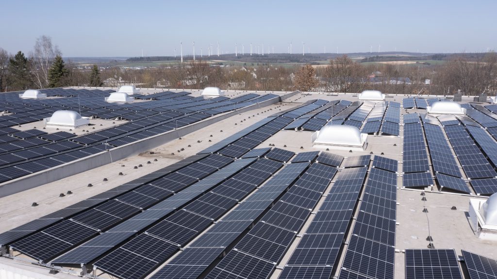 Photovoltaik auf Dachflächen - Hallenansicht mit Windrädern